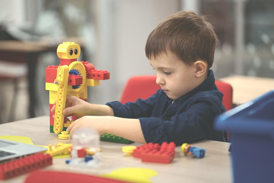 Little kid boy having fun with building and creating robot.