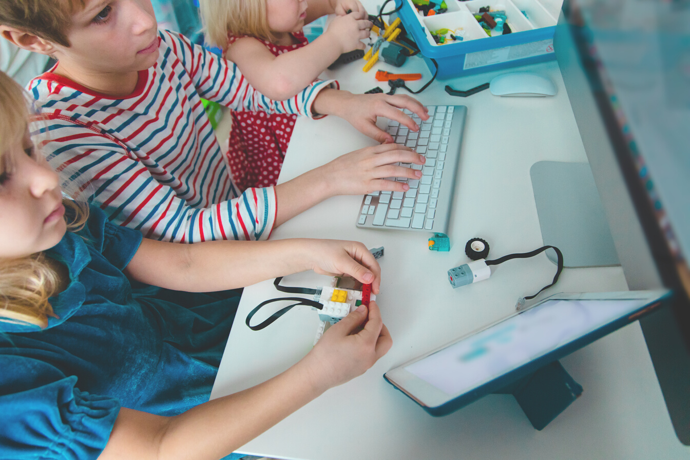 kids building robot and programming it with touch pad and computer