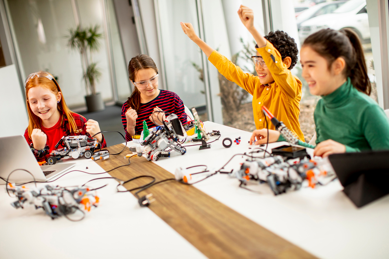 Happy kids programming electric toys and robots at robotics classroom